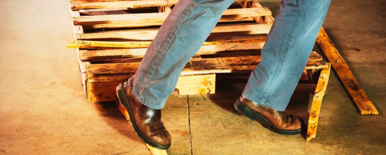 warehouse safety. a person trips of a damaged pallet in a warehouse.