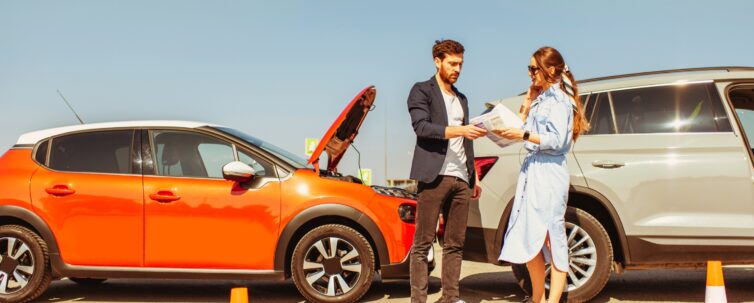 man and woman arguing standing together on the road with their cars on the background