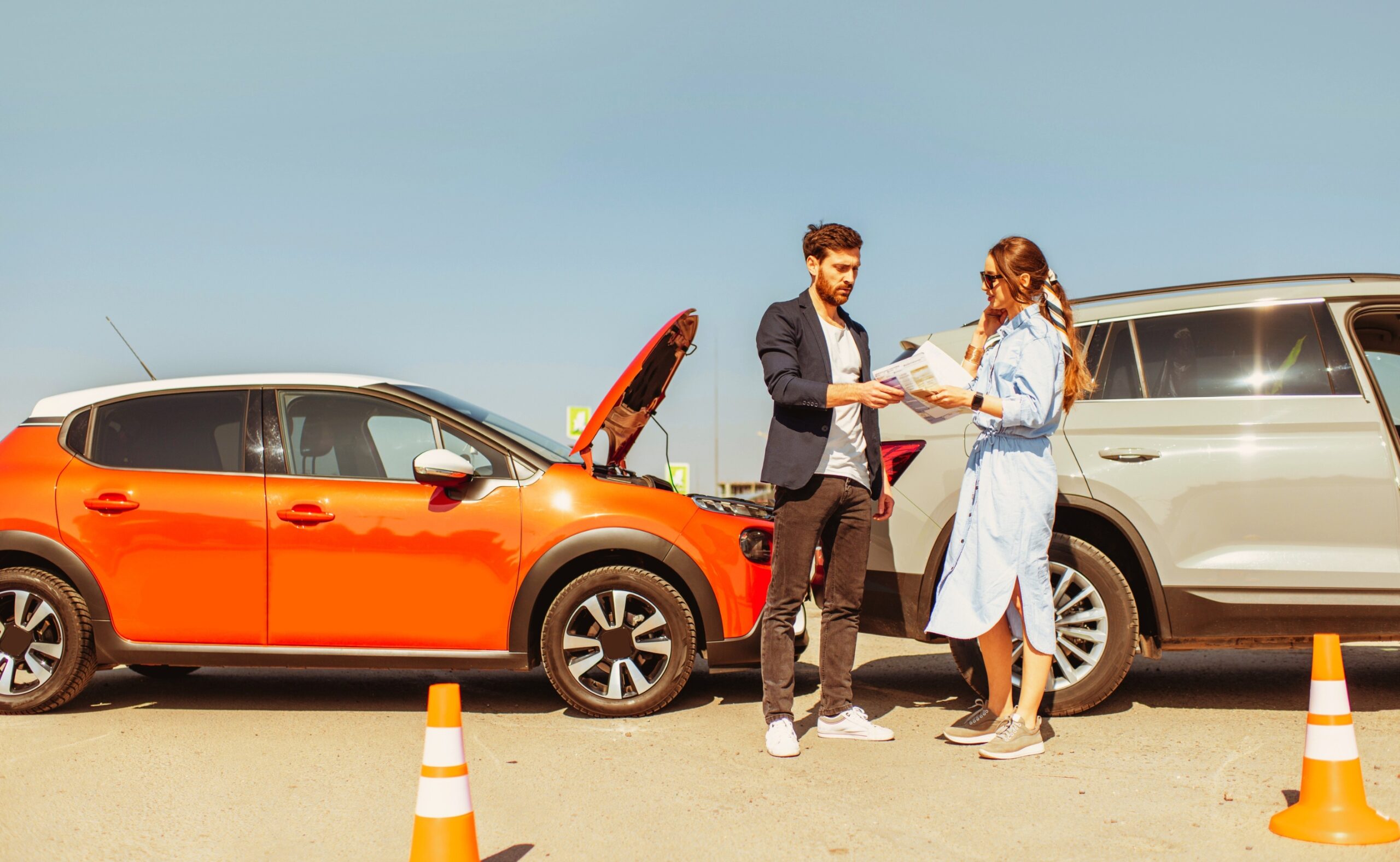 man and woman arguing standing together on the road with their cars on the background