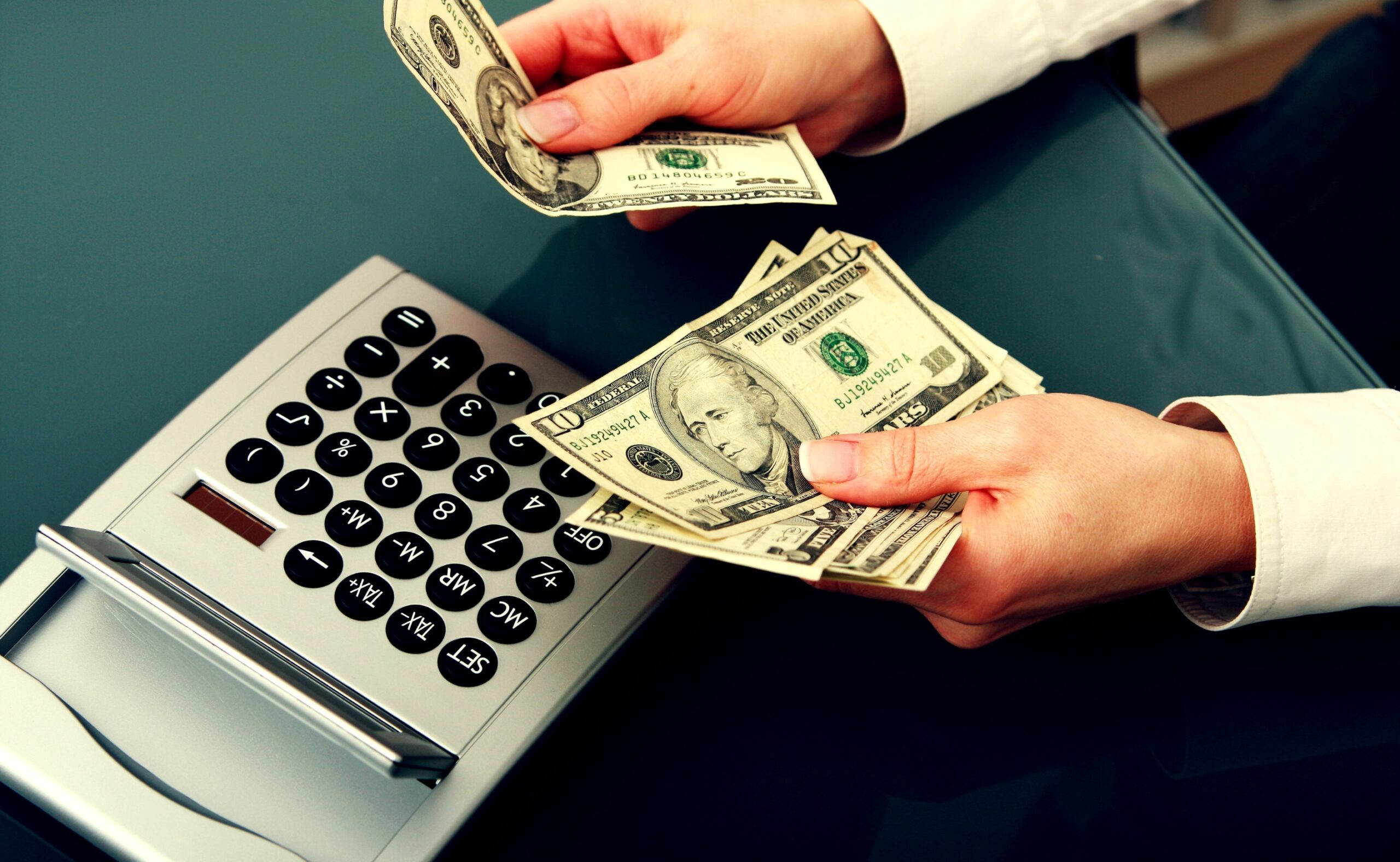 man with money on hand. there is a calculator on the table