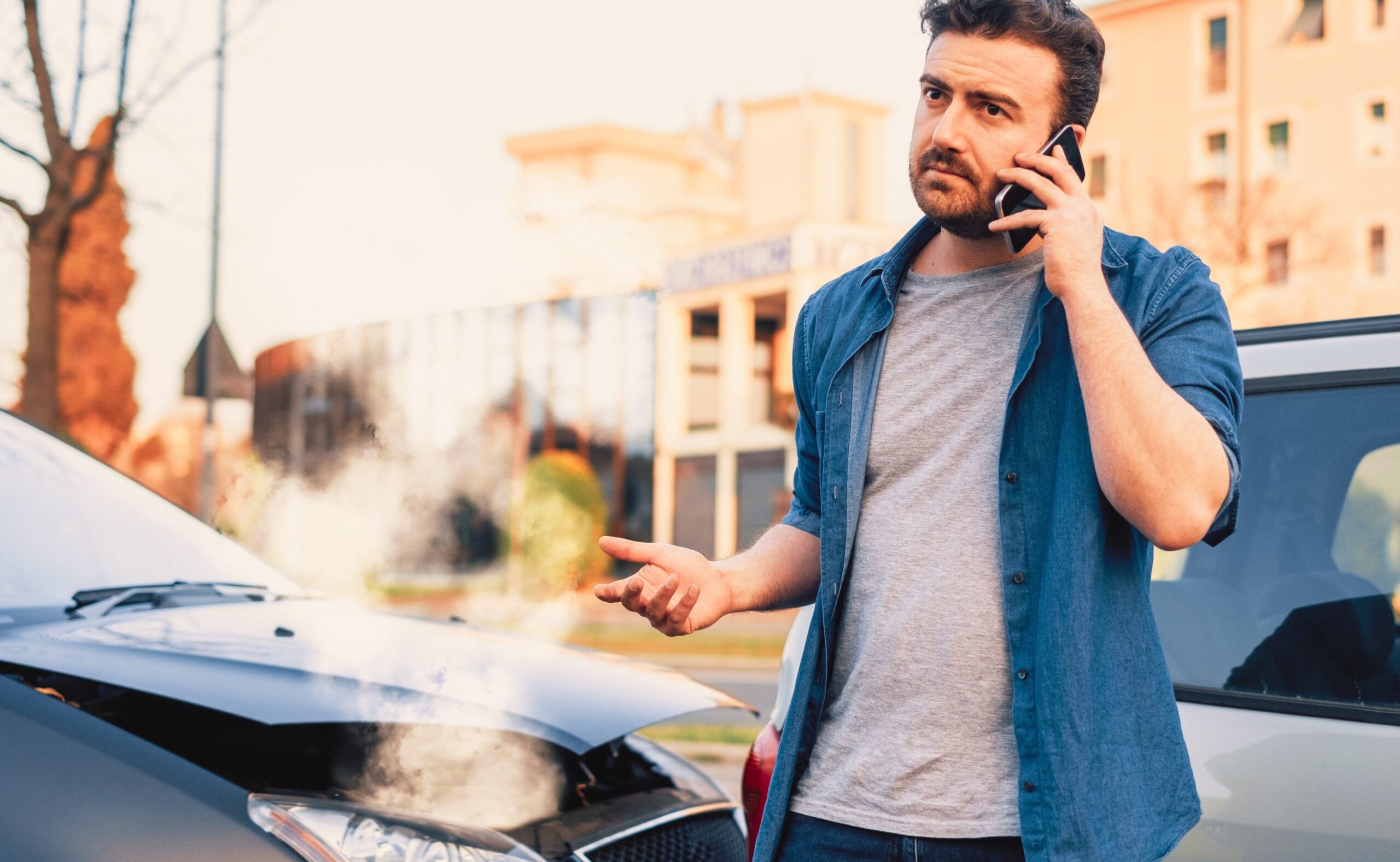 Man calling roadside service after car crash