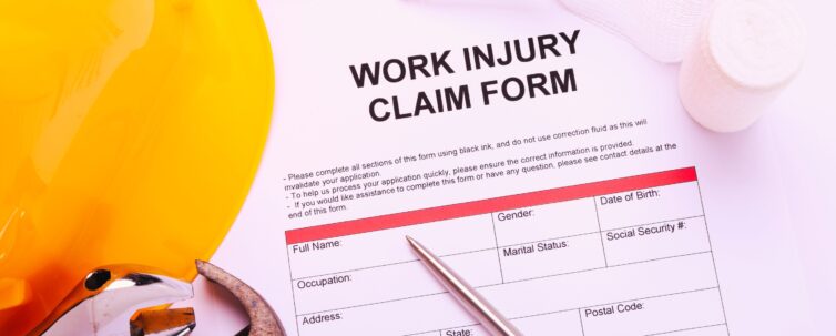 Work Injury claim form next to some tools and protective helmet