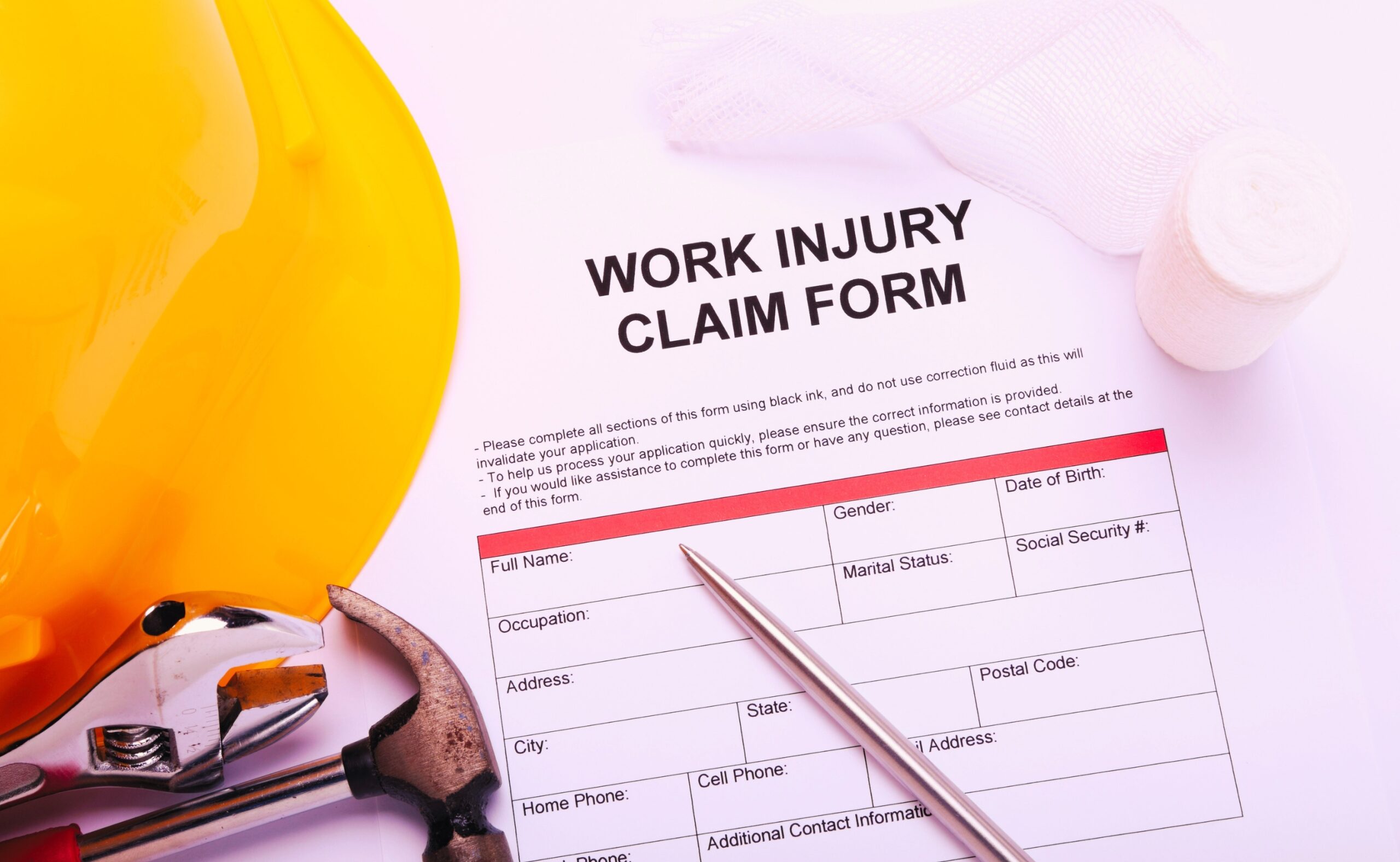 Work Injury claim form next to some tools and protective helmet