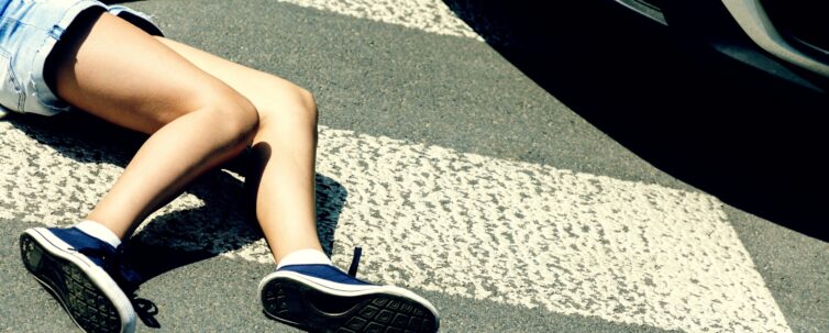 Victim of a traffic accident on pedestrian crossing next to a car