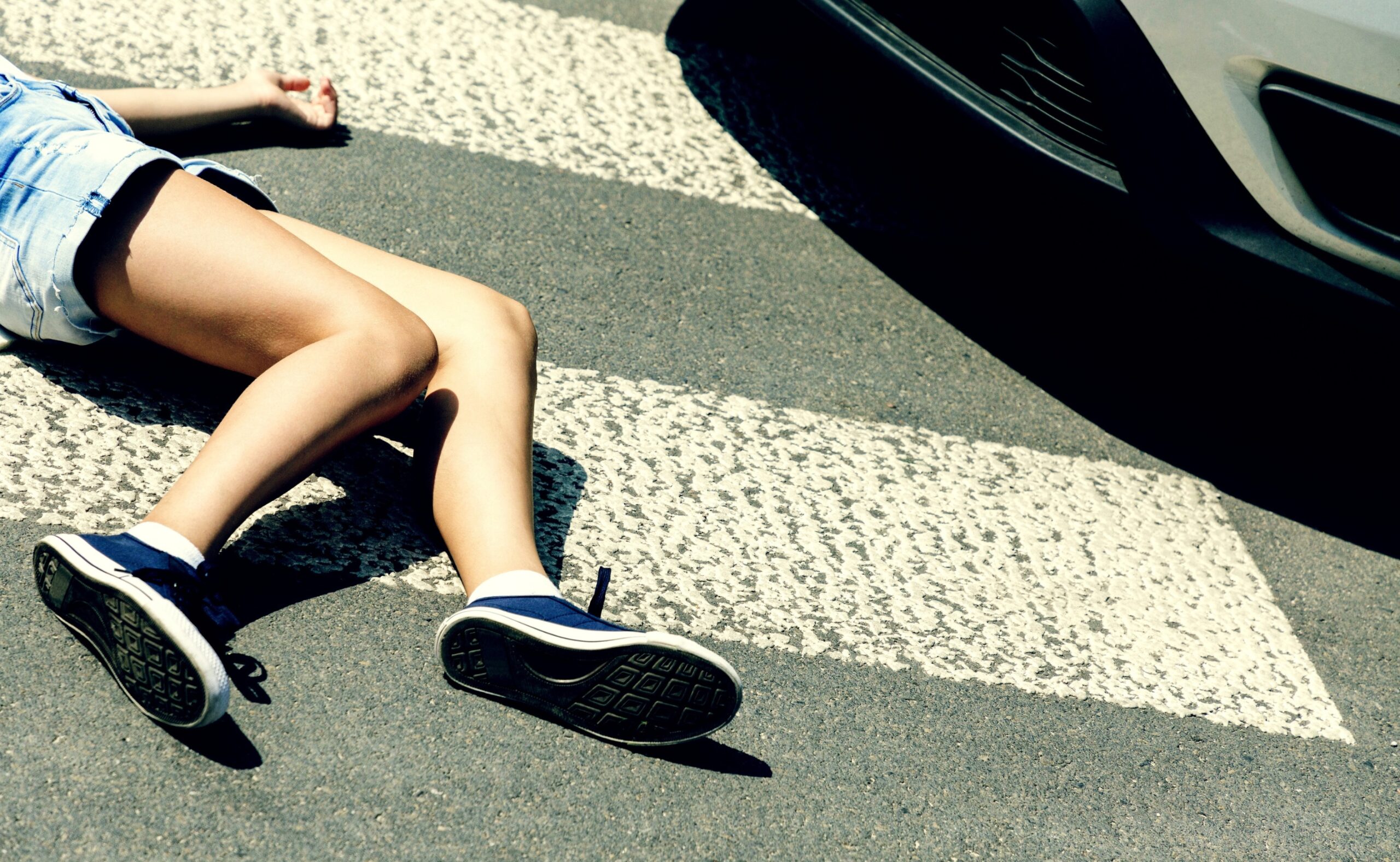 Victim of a traffic accident on pedestrian crossing next to a car